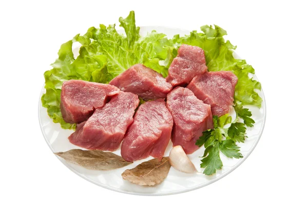 Trozos de carne cruda en un plato blanco se aísla en un respaldo blanco —  Fotos de Stock