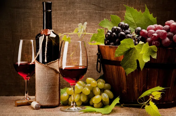 Bodegón con botellas de vino, vasos y uvas — Foto de Stock