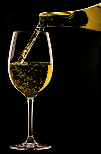 Gieten van een glas wijn op zwarte achtergrond. — Stockfoto