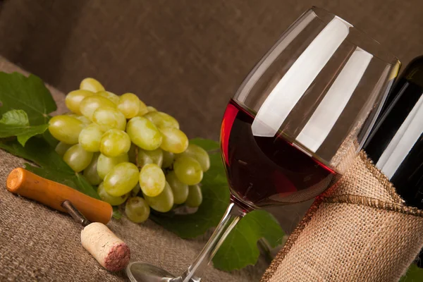 Bodegón con botellas de vino, vasos y uvas Imagen de archivo