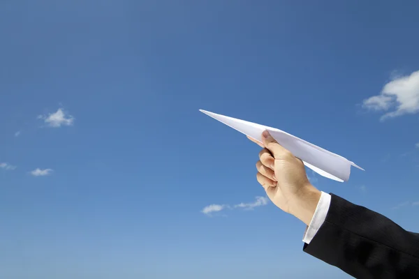 Mano di uomo d'affari che lascia volare un aeroplano di carta sopra il cielo blu — Foto Stock