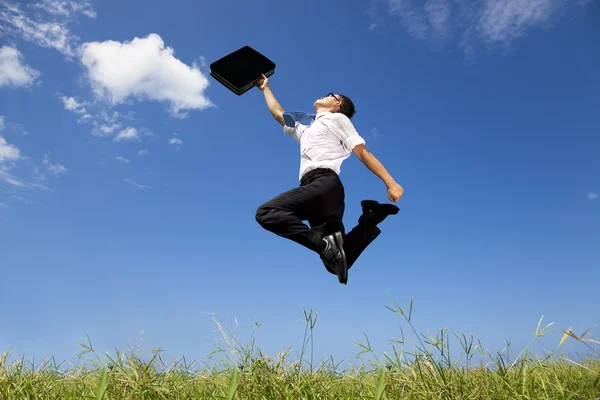 Happy and successful businessman jumping on the field — Stock Photo, Image