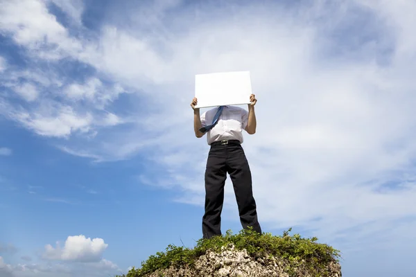 Businessman standing on a peak and holding blank billboard — Stock Photo, Image