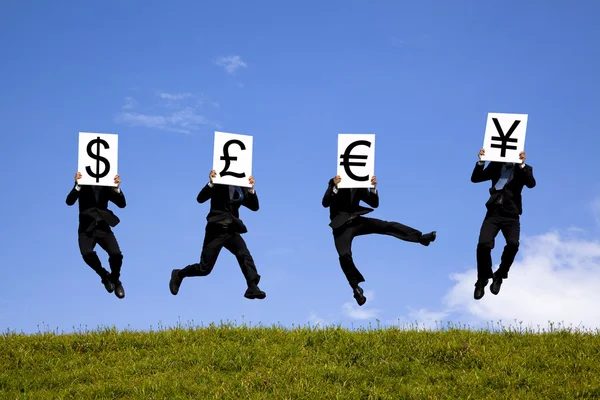 Empresario saltando y sosteniendo 4 diferentes signos de moneda. dólar, estanque , — Foto de Stock