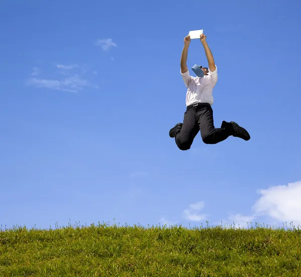 Feliz hombre de negocios sosteniendo la almohadilla táctil y saltando en la colina — Foto de Stock