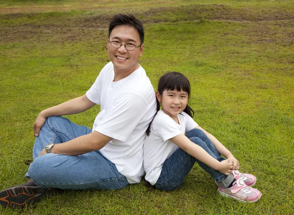 Glad pappa med dotter sitter på gräset — Stockfoto