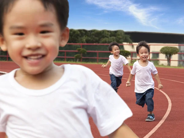 Šťastné děti běží na dráze stadionu — Stock fotografie