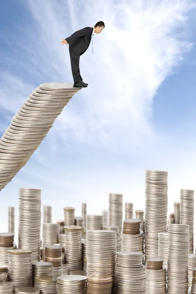 Удивленный бизнесмен, стоящий на денежной лестнице и смотрящий много монет — стоковое фото