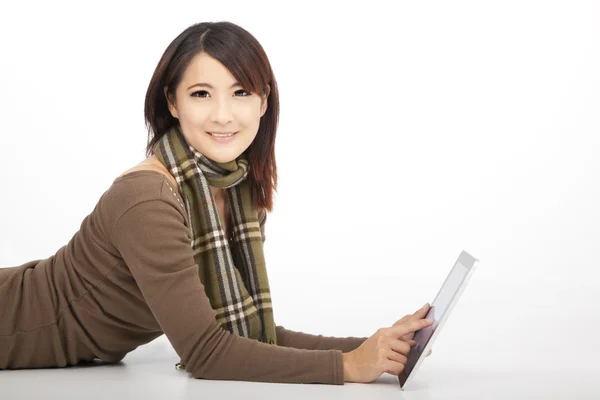 Mujer joven sonriente con una tableta PC mientras está acostado en el suelo — Foto de Stock