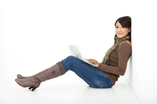 Улыбающаяся молодая женщина работает на ноутбуке, сидя на полу — стоковое фото