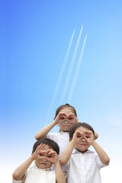 Üç mutlu çocuklar üzerinden göğe uçan uçak izlerken — Stok fotoğraf