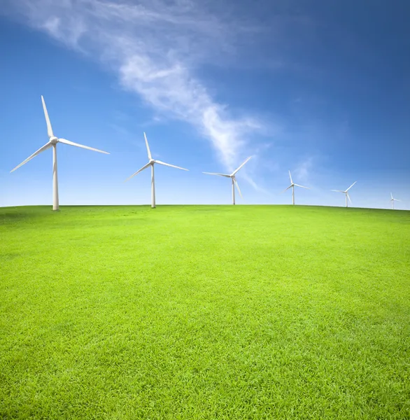 Ветряные турбины в зеленом поле с облачным фоном — стоковое фото