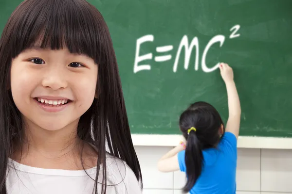 Happy girls by chalkboard with e=mc2 — Stock Photo, Image