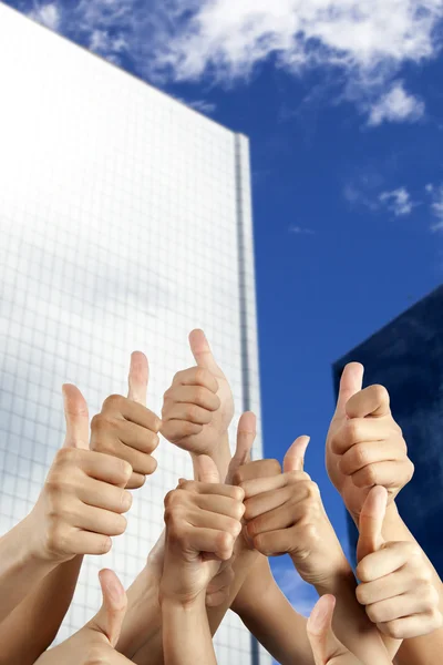 S рука с большими пальцами вверх перед современным зданием — стоковое фото