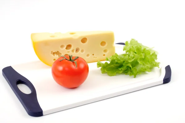 Cheese, tomato and salad sheet on a white board — Stock Photo, Image