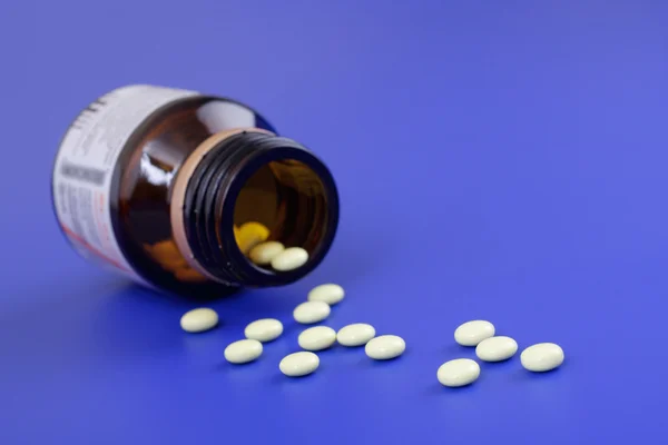 Gemorste tabletten en geneeskunde fles. tabletten op een blauwe pagina — Stockfoto
