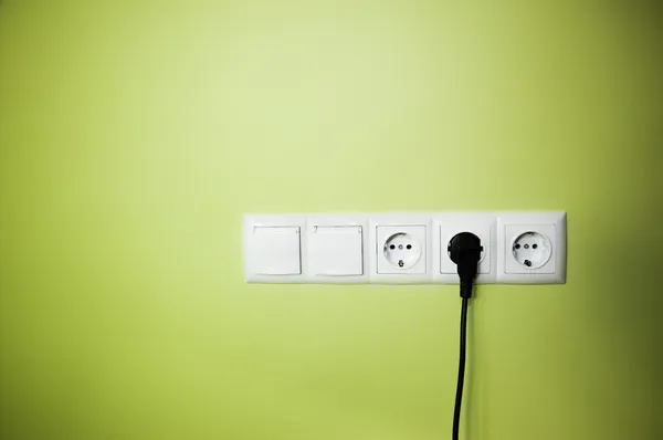 电气的墙上插座上绿色背景 — 图库照片