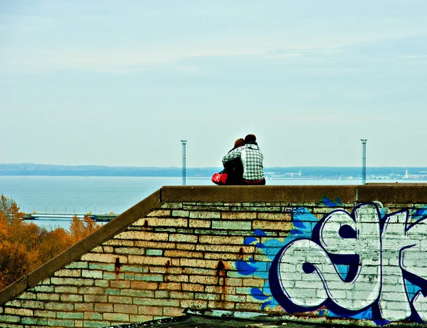A couple sitting on the brick wall. — Stock Photo, Image