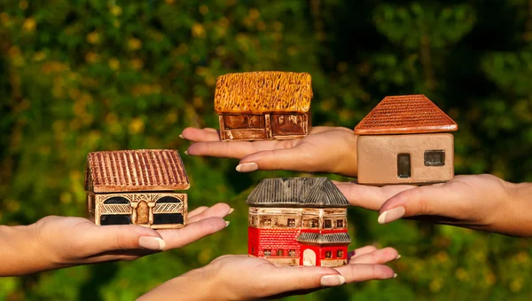 Cuatro casas diferentes en manos humanas Imagen de archivo