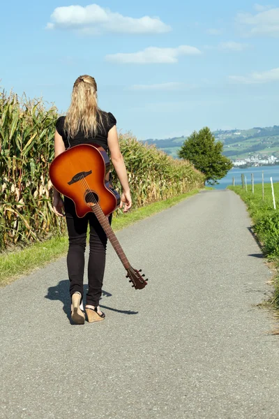 Chitarrista che cammina lungo la strada di campagna — Foto Stock