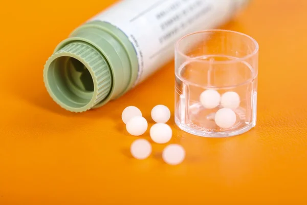 Comprimidos homeopáticos, recipiente em laranja — Fotografia de Stock