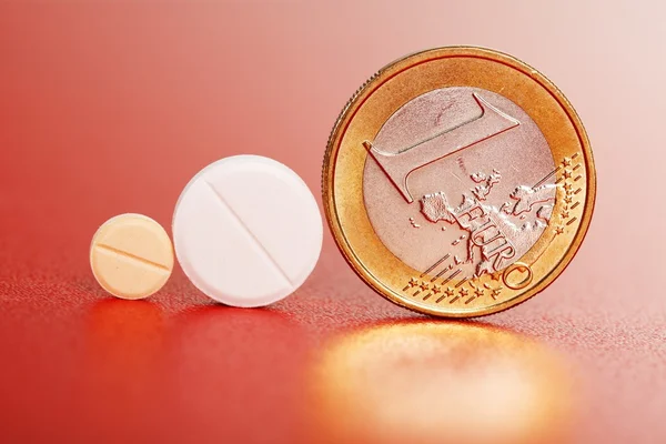 Comprimidos standig ao lado de uma moeda de euro — Fotografia de Stock