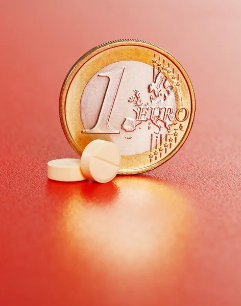 Дві таблетки перед однією монетою євро — стокове фото
