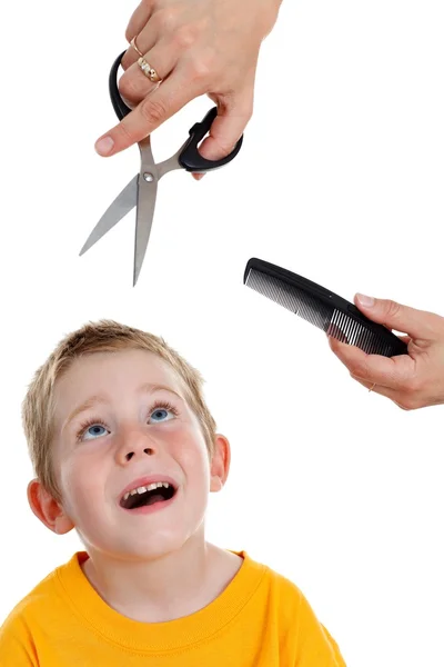 Испуганный маленький мальчик смотрит на ножницы и расческу — стоковое фото