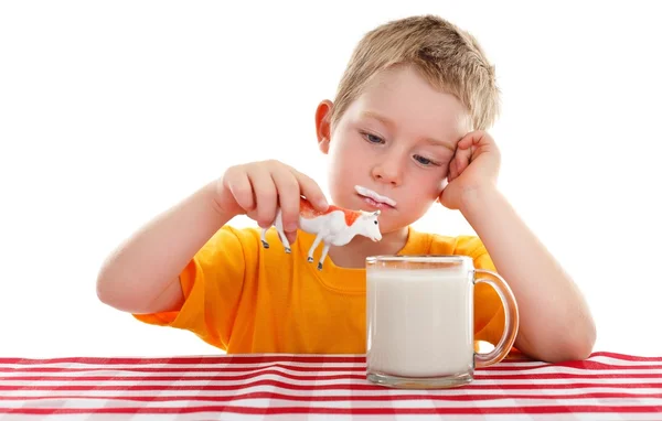 Mladý kluk hraje s hračka kráva za sklenici mléka — Stock fotografie