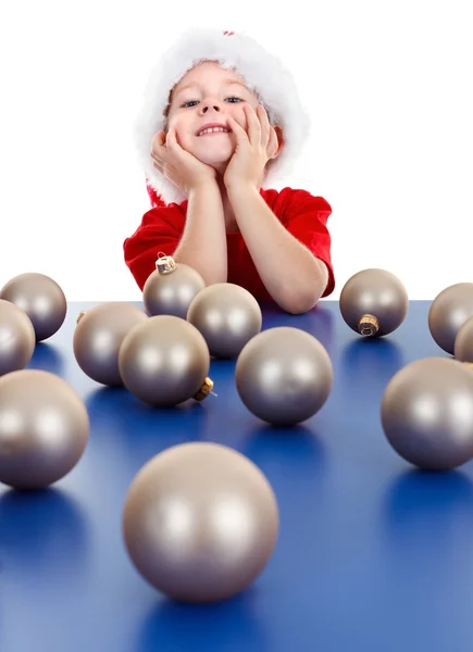 Little boy sitting behind Christmas ornaments — Stock Photo, Image