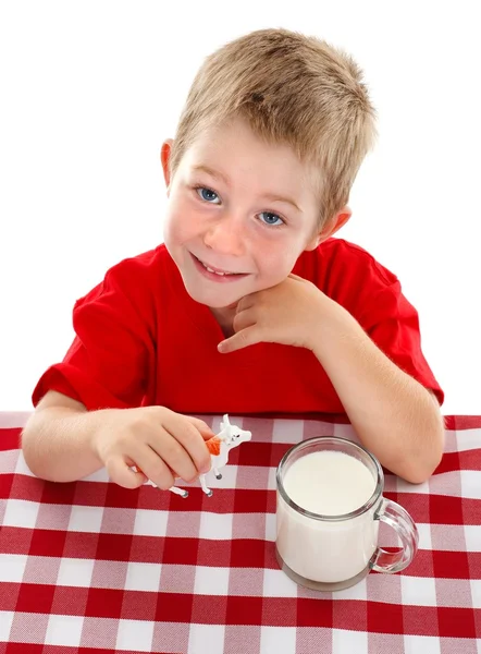 Fiatal gyerek játszik a játék tehén közelében pohár tej — Stock Fotó
