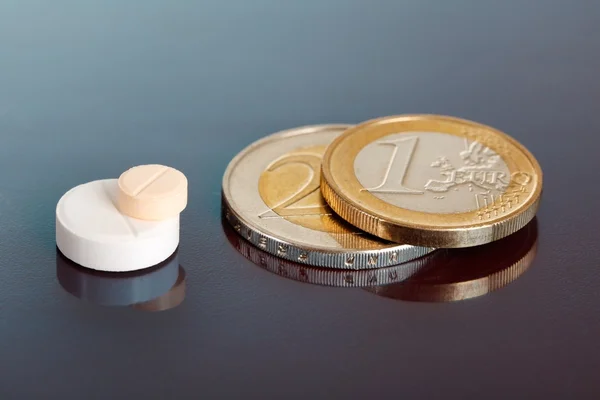 Comprimidos empilhados perto de par de moedas de euro — Fotografia de Stock