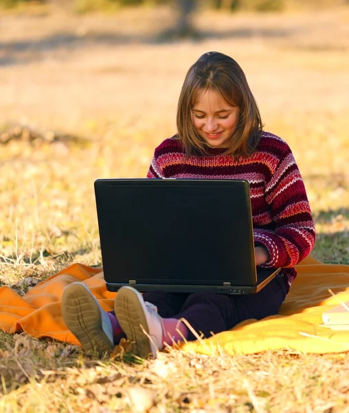 女孩坐在户外用的笔记本电脑 — 图库照片