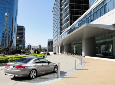 Luxury car near modern building's entrance clipart