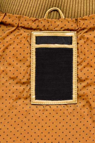 Etichetta in pelle e jeans scuri su tessuto punteggiato giallo — Foto Stock