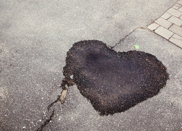 Mancha húmeda oscura sobre asfalto en forma de corazón —  Fotos de Stock
