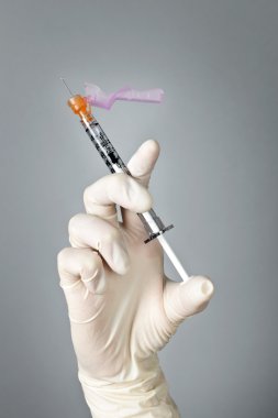 Syringe held by gloved hand clipart