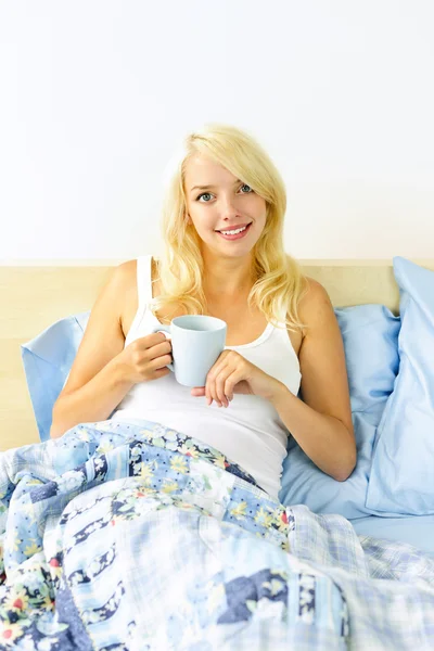 Όμορφη γυναίκα που κάθεται στο κρεβάτι με φλιτζάνι καφέ — Φωτογραφία Αρχείου