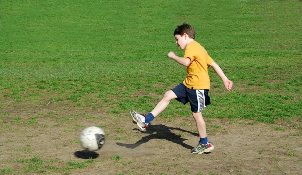 Мальчик пинал футбольный мяч — стоковое фото