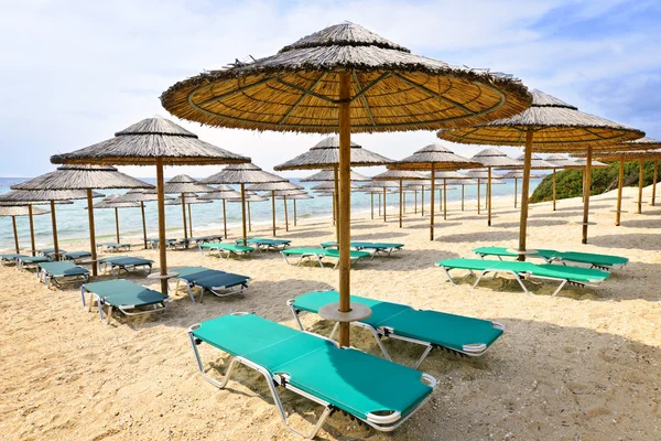 Beach umbrellas on sandy seashore — Stock Photo, Image