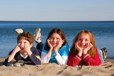 Three children on a beach clipart