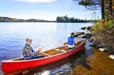Canoeing near lake shore clipart