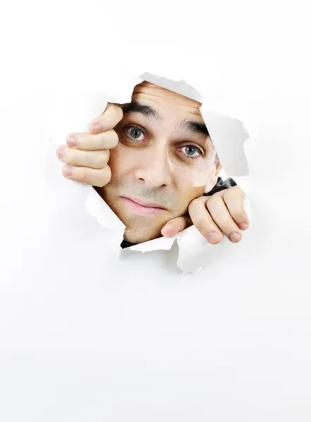 Cara mirando a través del agujero en papel — Foto de Stock