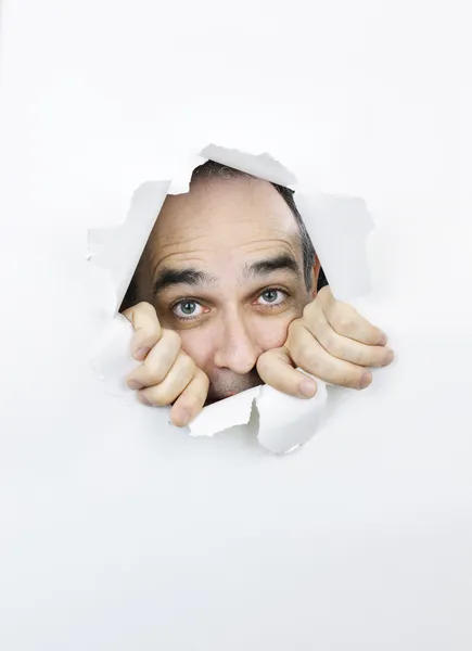 Cara asustada mirando a través de un agujero en papel — Foto de Stock