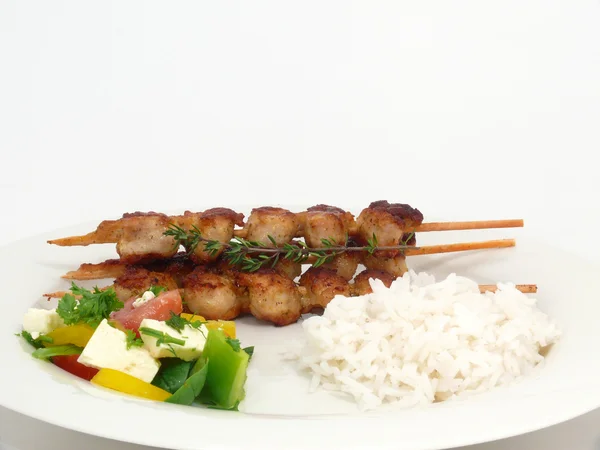 Grilled turkey kebabs on rice with salad — Stock Photo, Image