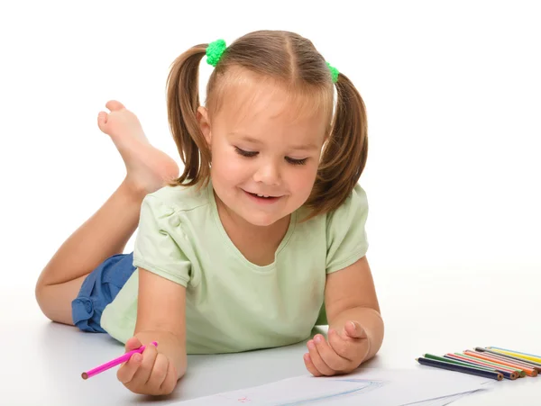 Маленькая девочка рисует, лежа на полу — стоковое фото