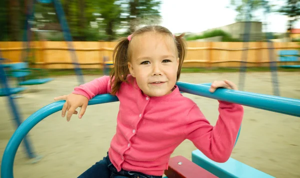 Cute little girl is riding on merry-go-round — Stock Photo, Image