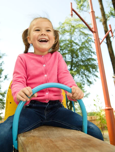 Cute little girl is swinging on see-saw — Stock Photo, Image