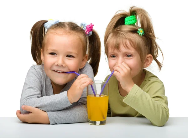 Zwei kleine Mädchen trinken Orangensaft — Stockfoto