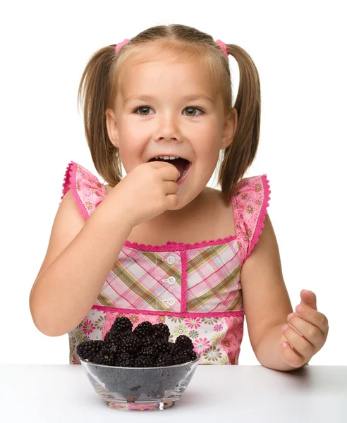 Веселая маленькая девочка ест ежевику — стоковое фото